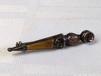 Side view of the antique pin brooch showing the tapered sterling silver body with tiger's eye inlay and rounded amethyst setting.