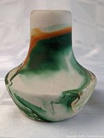 Front view of Nemadji pottery vase showing marbled green, orange and cream glaze pattern and shape.