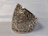 Side view showing detailed filigree scroll and leaf pattern in silver on the vintage ring.