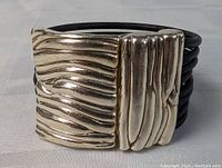Front view of the bracelet showing the textured silver clasp on black leather bands.