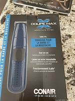 Front of box showing the Conair Coupe Max cordless beard and mustache trimmer in dark blue with black grip area and stainless steel blades, indicating it's battery operated and designed for beard and mustache trimming.