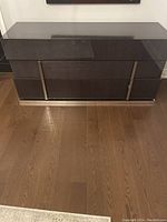 Full front view of dark wood glossy bedroom drawer chest on wooden floor