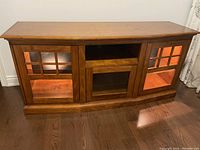 Front view of wooden TV stand showing three compartments and lighting