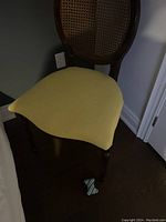 Front angled view showing the yellow upholstered seat and front legs of the wooden chair.