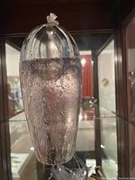 Photo showing a 7-inch tall clear glass oil candle with internal air bubbles and a sealed top stopper.