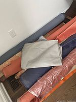 Several fabric bolts stacked horizontally including rust, blue, orange, beige in various textures