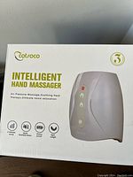 Photo of the box of the Cotoco Intelligent Hand Massager showing product features and brand logo.