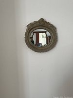 Front view of round mirror with thick ornate frame, showing decorative details and clear reflective glass.