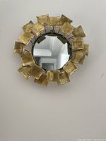 Round modern wall mirror with gold square metallic pieces forming the frame.