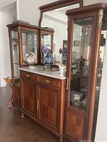 Front angle view of antique wooden buffet with marble top and large central mirror, side glass display cabinets with shelves visible