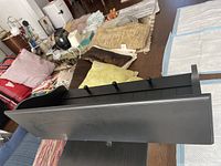 Top-down angle showing the front and side profile of the black wooden shelf with hooks.