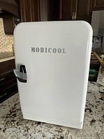 Closed view of the Mobicool branded small portable fridge showing its front side and latch handle