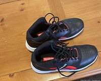 Side view of the black Reebok indoor basketball shoes showing red accents and white sole