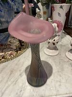 Pink ruffled top Rueven glass vase on a marble surface with a decorative multicolored base.