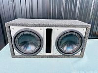 Front view of carpeted subwoofer enclosure showing both Alpine subwoofers and center port.