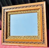 Front view of the rectangular antique oak frame mirror showing oak and gilt embossed floral decoration.