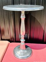 Front view of the metal round top end table showing its pedestal base and circular top.