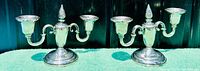 Front view of both two-arm candelabras side by side on green cloth background