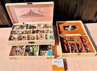 Full view of two jewelry boxes filled with assorted jewelry pieces such as watches, necklaces, brooches, and earrings