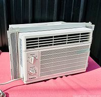 Front view of the white GoldStar WM5000 window air conditioner unit showing control dials and ventilation grille, with expandable side panels visible.