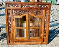 Front view of closed shuttered teak wood mirror with intricate carved panels featuring floral and geometric designs.