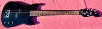 Full front view of black Jaguar bass guitar laid on pink cloth