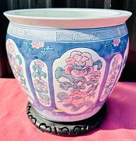 Front and side view of large Chinese porcelain planter with blue background and pink floral chinoiserie panels on wood stand
