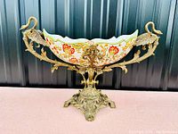 Front view of porcelain centerpiece bowl with floral pattern and bronze swan mounts on ornate bronze base
