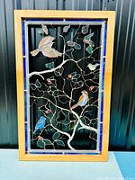 Full view of the stained glass panel in oak frame, showing birds perched on branches with red berries and the blue border.