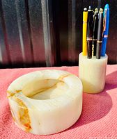 Photo showing carved round vessel and cylindrical pen holder with pens