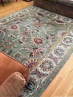 Full view of rectangular wool area rug on hardwood floor beneath seating