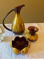 Three Blue Mountain Pottery items: a pitcher, vase, and bowl with brown and yellow glaze.