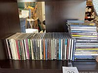 Photo of 30 CDs stacked vertically and horizontally showing spines and covers, with visible titles and artists.