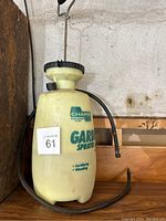 Side view of the yellow Chapin garden sprayer showing branding, hose coiled around and pump handle on top.