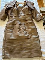 Gold Jean DeLys dress laid flat showing horizontal pleats and sweetheart neckline with matching jacket