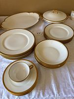 Full set of Theodore Haviland Limoges porcelain dinnerware arranged on a white cloth, including plates, bowls, cup and saucer, large serving platter, and covered serving dish with lid. Gold trim pattern visible on all pieces.