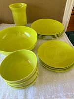 Yellow-green melamine dish set consisting of 6 plates, 4 bowls, and 2 larger bowls shown arranged on a table.