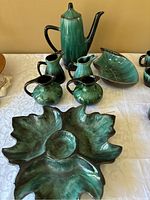 Full set including coffee pot, creamers, bowl, and leaf-shaped serving dish on a white tablecloth.