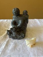 Front view of the Inuit soapstone carving depicting mother with child and horse figure, alongside a small light-colored animal figure.