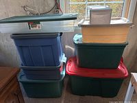Stack of seven plastic storage containers of varying colors and sizes placed in front of a window, showing the lot composition