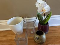 Four vases arranged with faux orchid plant.