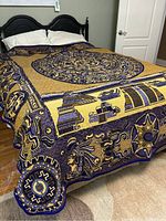 Blanket spread across bed showing full Mayan calendar central design with border motifs and golden background.