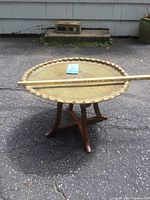 Side view of the vintage brass tray coffee table showing the tray on wood folding base with a measuring stick across the tray to indicate size.