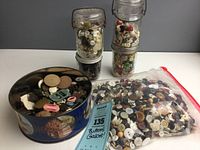 Photo of three glass jars, a tin filled with assorted buttons, and a plastic bag full of numerous buttons in various colors and sizes.