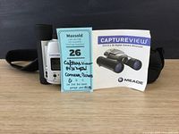 Front view of Capture View binoculars with manual and blue Maxsold tag.