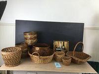 Photo showing eight baskets and a champagne themed wooden tray arranged on a shelf, various natural browns and wicker materials visible.