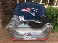 Front view of inflatable chair showing Patriots logo on navy blue backrest, silver armrests with cup holders, and red base with Patriots script.