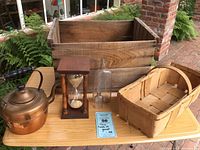 Full lot shown on table outside, includes wooden apple crate, copper kettle, hourglass, glass bottles, and basket.