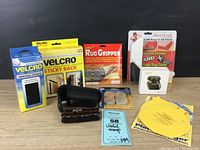 Photo of all items arranged neatly showing multi tool case, Velcro packs, earbuds, rug gripper, and carpet corner guards