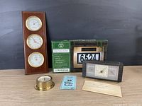 Full view of lot showing solar house number in box, wooden weather gauge panel with three round dials, brass barometer, and rectangular vintage weather gauge device.
